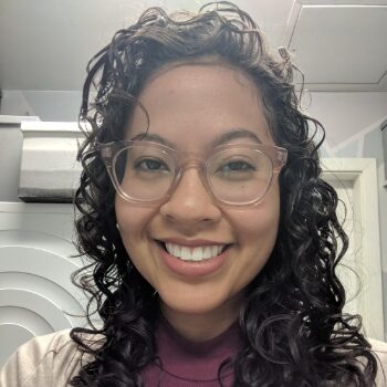 Photo of a Black and Asian woman with curly dark hair and glasses
